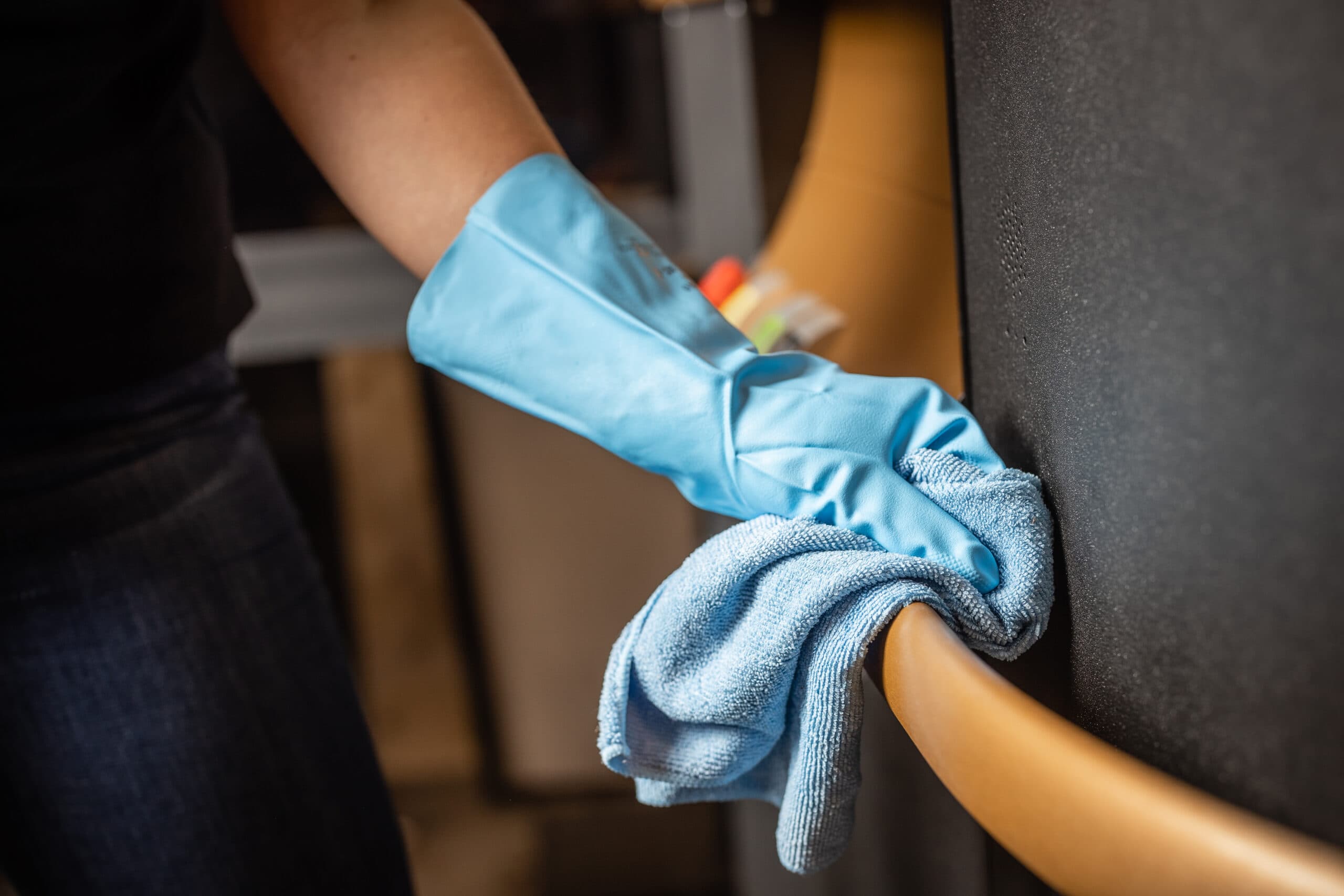 cleaning lift handrail with gloves and cloth