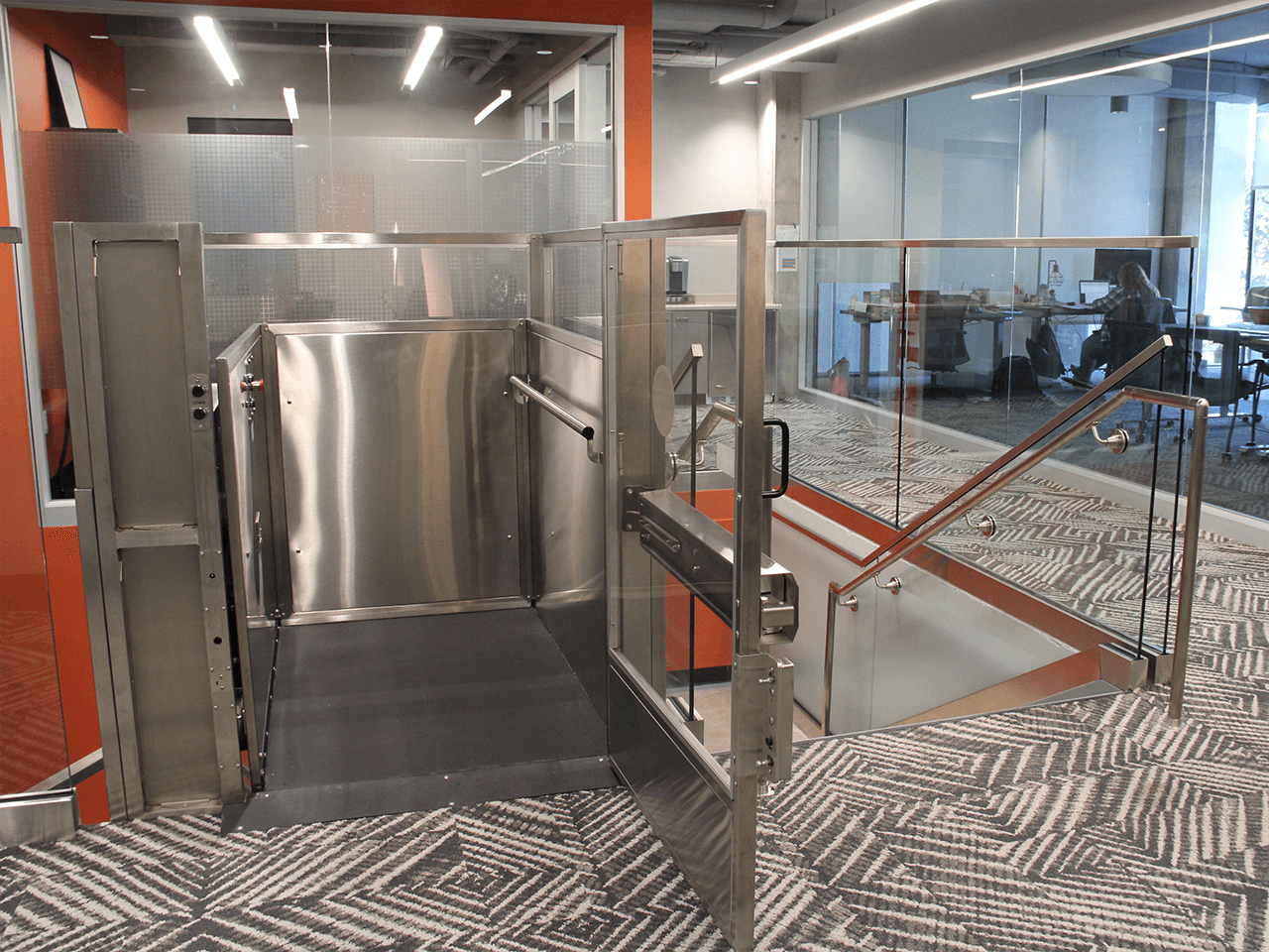 enclosed lift plexi in stainless steel with gate open at upper landing