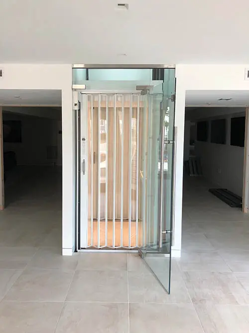 beach house glass elevator lit up white and clear accordion door