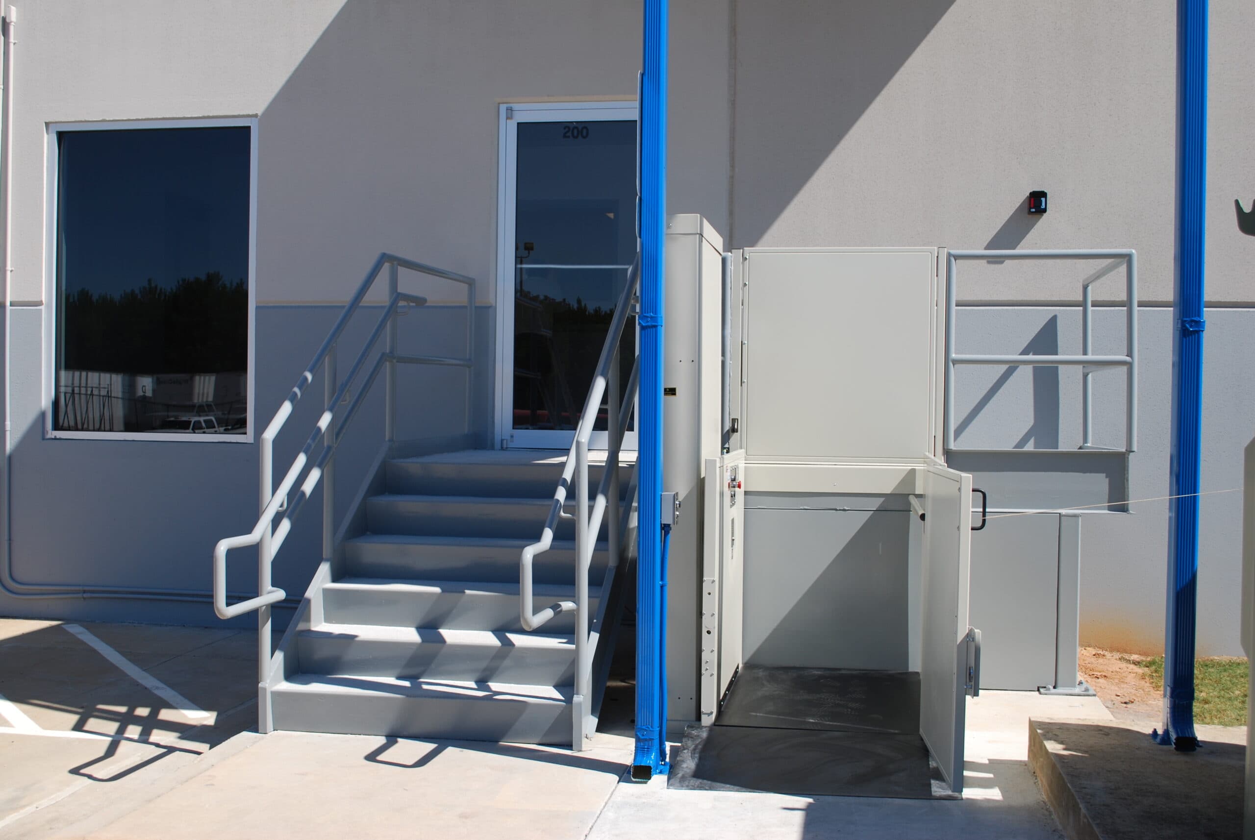 unenclosed vertical platform lift outdoor in commercial setting showing lower landing